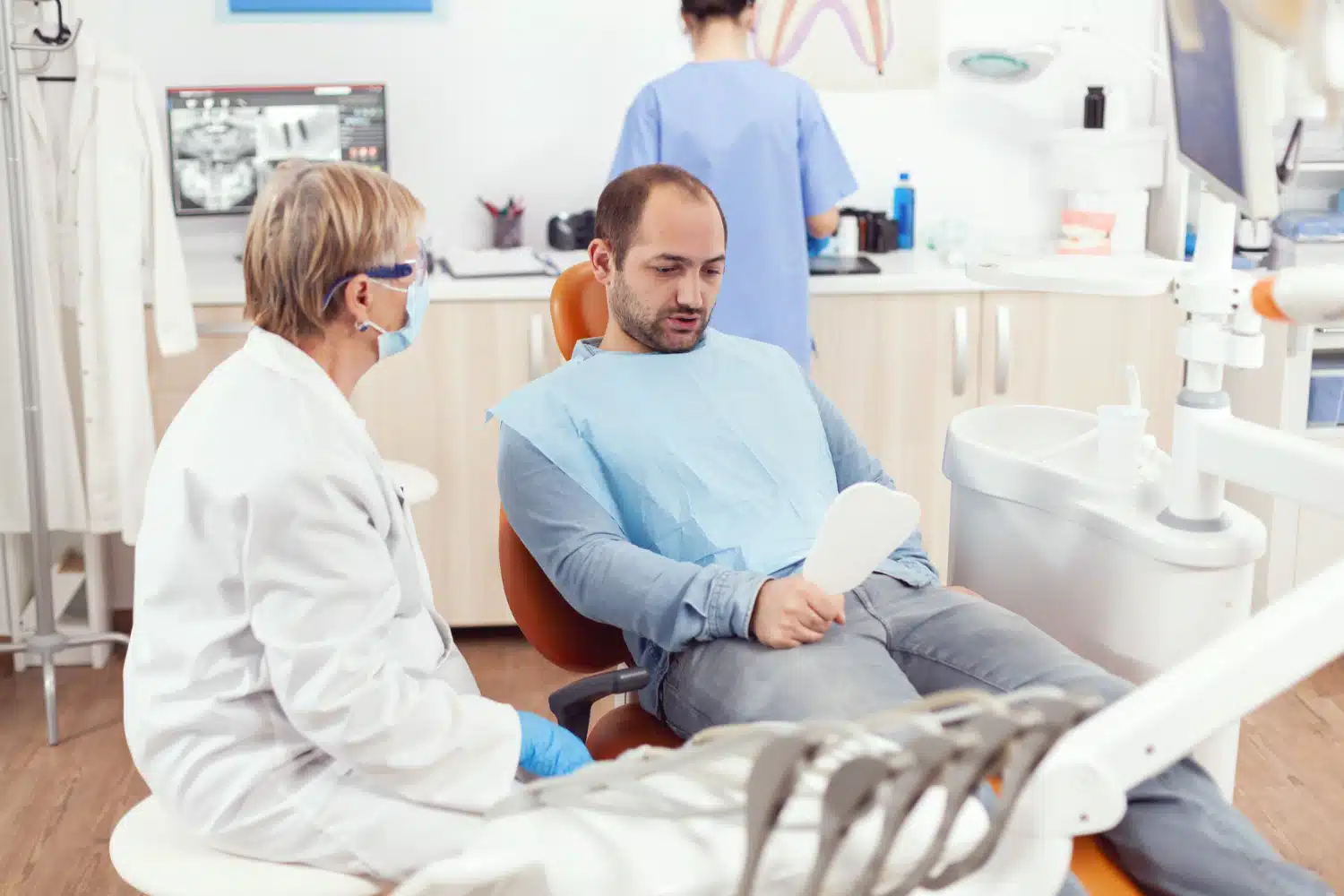 Patient consultation with orthodontist in dental office, discussing treatment options and insurance coverage for braces.