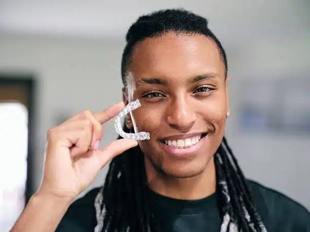 young-man-holding-dental-aligners Smiling patient holding up his dental aligners