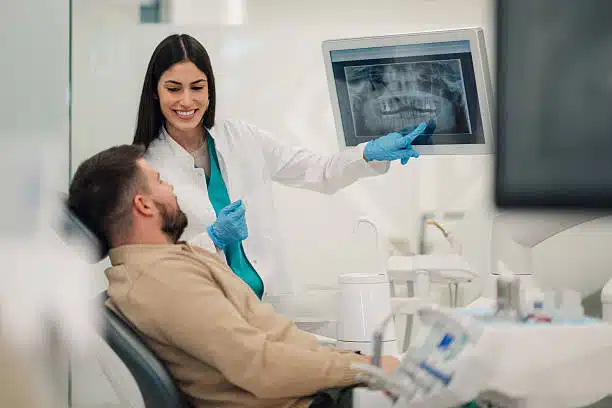 Female dentist showing a teeth x-ray to a male patient in a dental clinic Patient during consultation with dentist